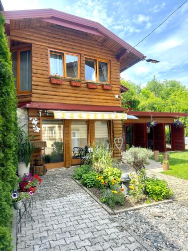 ein Holzhaus mit einer Terrasse und Blumen in der Unterkunft Apartmani Lara&Sara in Bihać
