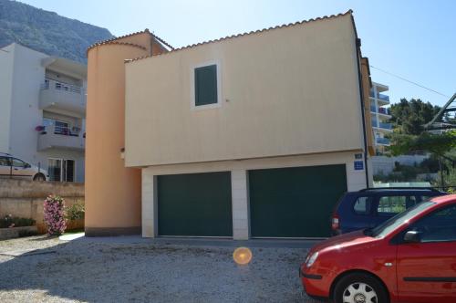 a building with two garage doors and a red car at Apartment Garden View Makarska in Makarska