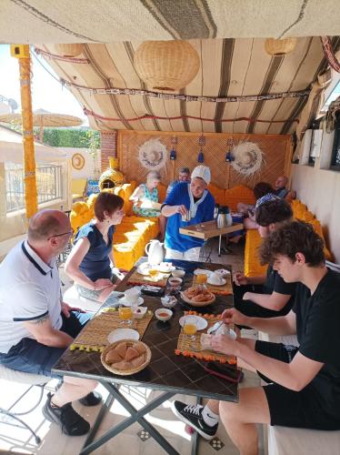 een groep mensen die aan een tafel zitten en eten bij Riad Les Gazelles D'Orient Marrakech in Marrakesh