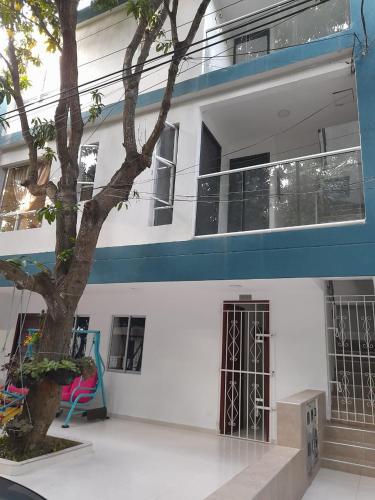 a white building with a tree in front of it at Apartaestudio Cartagena 2P in Cartagena de Indias