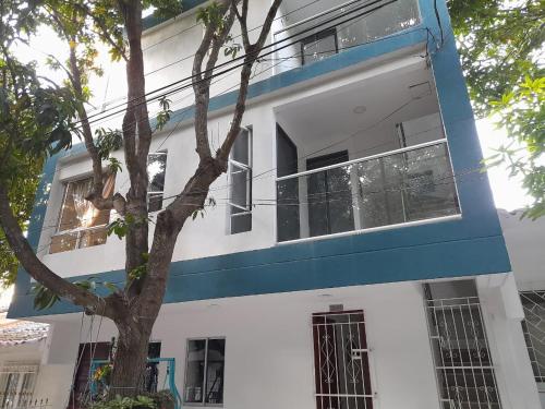 un edificio azul y blanco con un árbol delante en Apartaestudio Cartagena 2P en Cartagena de Indias