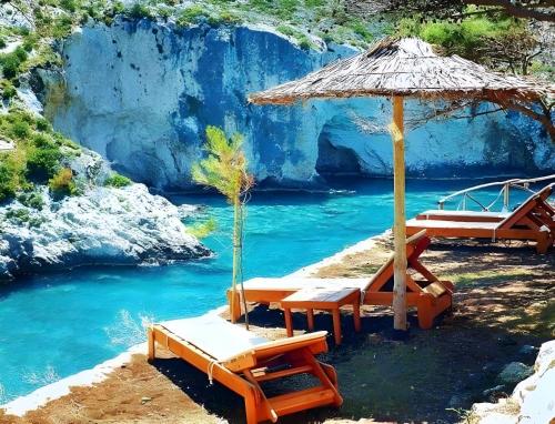 uma praia com cadeiras e um guarda-sol e água em Country House in Agios Leon em Agios Leon