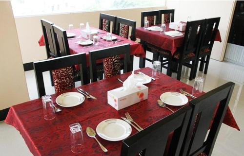 a dining room with a red table set with plates and silverware at White Inn luxury Residential Hotel in Chittagong