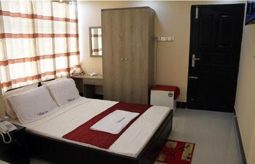 a bedroom with a bed and a sink and a door at White Inn luxury Residential Hotel in Chittagong