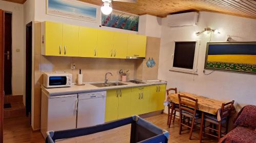 une cuisine avec des armoires jaunes et une table en bois dans l'établissement Apartments Alex, à Rovinj