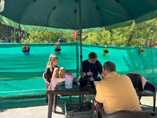 a group of people sitting at a table under an umbrella at Tiny Spot Hostel in Manāli