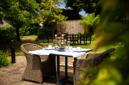 a table with wicker chairs and a white table cloth at Hartnoll Hotel & Spa in Tiverton