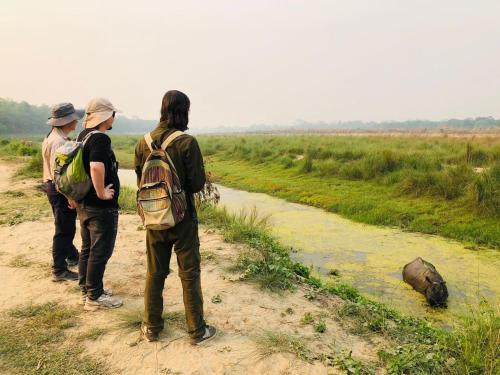 three people standing on a dirt road looking at a river at Hotel Tiger Tops Sauraha in Sauraha