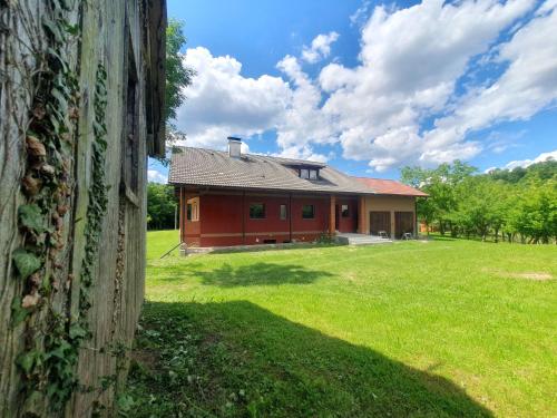 a large red house with a grassy field in front at Monk Apartment in Bosiljevo