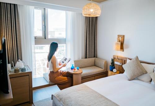 a woman sitting on a table in a hotel room at Hotel Resol Trinity Naha in Naha