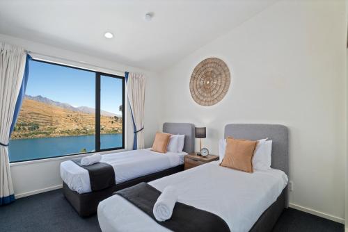 two beds in a room with a large window at Goldfield Holiday Home in Queenstown