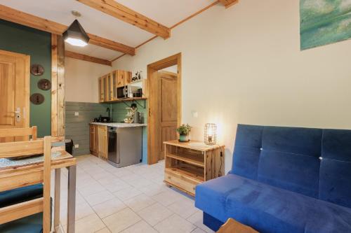 a living room with a blue couch and a kitchen at Jesteśmy Na Ty - Apartamenty in Lewin Kłodzki