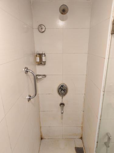 a shower in a white tiled bathroom at Regenta Place Bangalore, Cunningham Road in Bengaluru