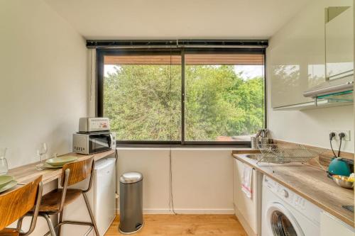 une cuisine avec une fenêtre, une table et des chaises dans l'établissement Le Petit Gerland - Agréable à 1 minute du métro B, à Lyon