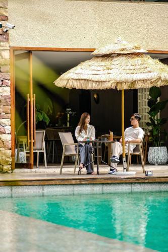 a man and woman sitting under an umbrella next to a pool at Pandora Vista Retreat in Zhangjiajie