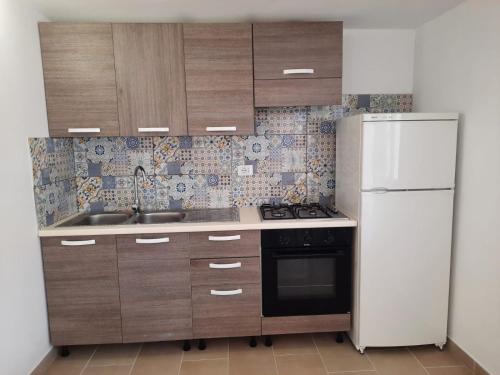 a kitchen with wooden cabinets and a white refrigerator at Perla Bianca in Marina di Lizzano