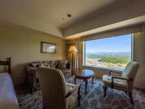 高山市にあるホテルアソシア高山リゾートのリビングルーム(ソファ、椅子、大きな窓付)