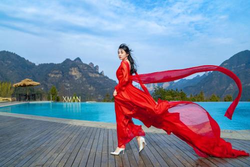 a woman in a long red dress standing next to a pool at XMAN Sunrise Peaks Resort--Free Pick-up in Zhangjiajie