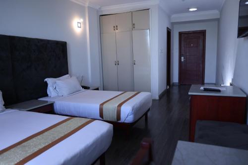 a hotel room with two beds and a cabinet at Trinity Hotel in Addis Ababa
