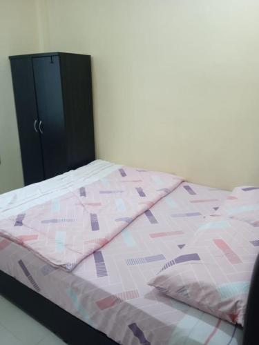 a bed with a pink and purple comforter and pillows at Selesa Homestay Jalan Gambang in Kuantan