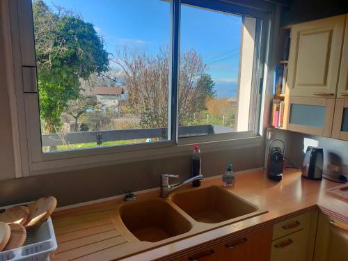 une cuisine avec un évier et une grande fenêtre dans l'établissement Maison au calme, à Marin
