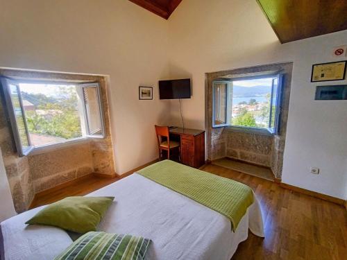 Miñortos的住宿－Casa do Fieiro，一间卧室设有一张床和两个窗户。
