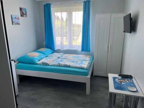 a bedroom with a bed with blue sheets and a window at Gaspard in Sarbinowo