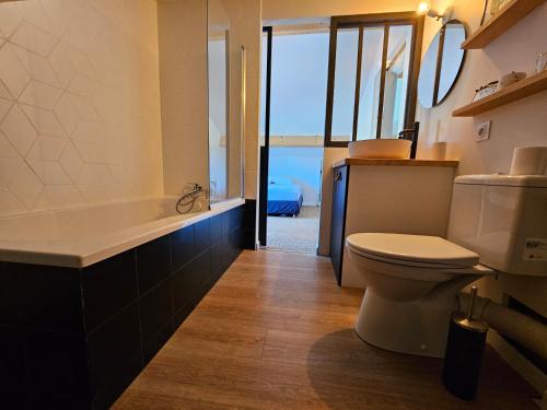 une salle de bain avec toilettes et baignoire dans l'établissement Maison de ville avec piscine, à La Teste-de-Buch