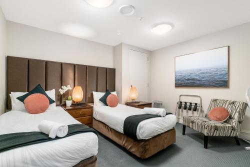 1 Schlafzimmer mit 2 Betten und einem Stuhl in der Unterkunft The Beacon - 2 Bedroom Town Center Apartment in Queenstown