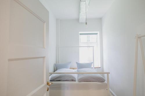 a bed in a white room with a window at NordseeEstate - Loft unter Reet mit Sauna in Tetenbüll