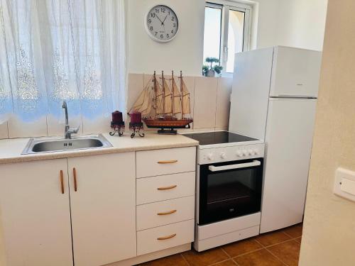 a kitchen with a sink and a white refrigerator at Estate Tsoukalas with Pool - Perfect for Large Groups Next to Laganas Offering Incredible Greek Hospitality By Villa Mana Gers in Ambelókipoi