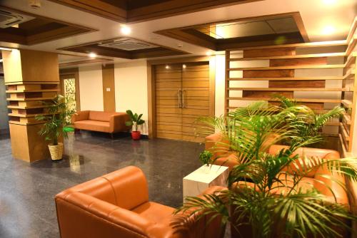 an office lobby with leather chairs and plants at Hotel Rishiraj, Nagaon in Nowgong