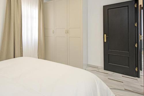 a bedroom with a white bed and a black door at Apartamento San Cayetano, By DaiMar in Armilla
