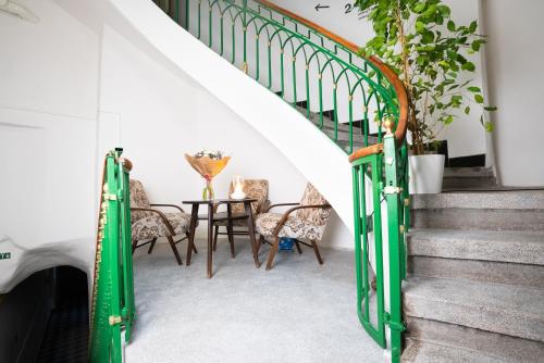 a staircase with green railings and a table with chairs at White Wolf House Hostel & Apartments in Prague