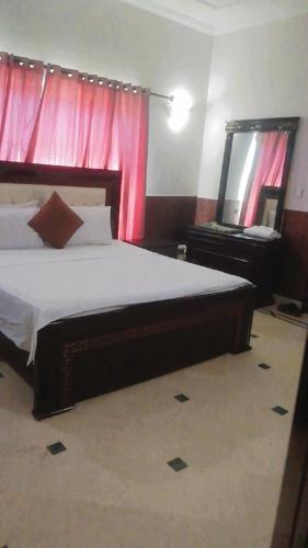 1 dormitorio con 1 cama grande y espejo en Overseas B&B Guest House, en Islamabad