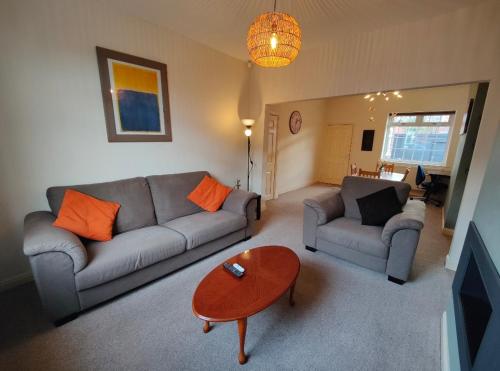 a living room with two couches and a table at Victorian Semi Detached House behind the High Street in Newton in Makerfield