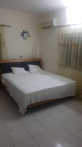 a bedroom with a white bed in a room at Guest House de Cotonou in Cotonou