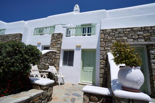 a white house with a green door and chairs at Bellissimo Resort in Agios Ioannis Mykonos