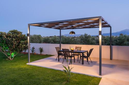 a patio with a table and chairs under a pergola at Aspect Luxury Apartments with Pool in Galangádhos