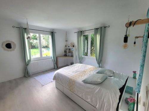 a white bedroom with a bed and two windows at Maison 3 chambres avec piscine in Josse