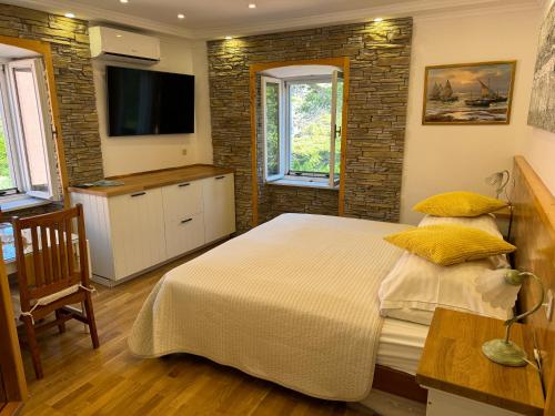 a bedroom with a bed with yellow pillows and a tv at Studio Lorena in Mali Lošinj