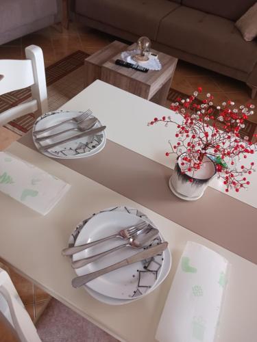 biały stół z płytkami i kwiatami w obiekcie Vangert Apartment w mieście Berat