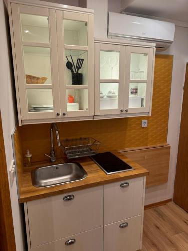 - une cuisine avec des placards blancs et un évier dans l'établissement Studio Lorena, à Mali Lošinj