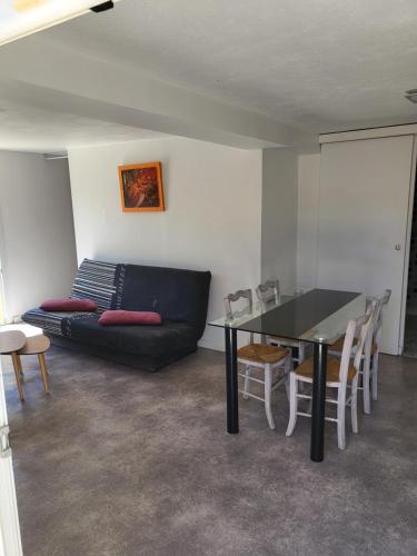 ein Wohnzimmer mit einem schwarzen Sofa und einem Tisch in der Unterkunft Jolie T2 indépendant dans une villa in Solliès-Ville