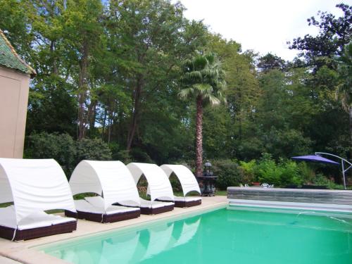 - une rangée de chaises blanches à côté de la piscine dans l'établissement Château Rieutort, à Saint-Pargoire