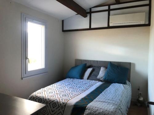 une chambre avec un lit avec des oreillers bleus et une fenêtre dans l'établissement Maison avec jardin, à Sainte-Maxime