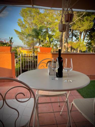 a white table with two glasses and a bottle of wine at Linden House Etna in Aci SantʼAntonio