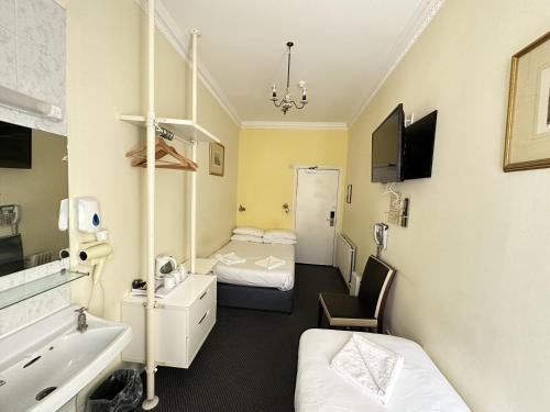 Habitación hospitalaria con 2 camas y lavamanos en Manor Hotel, en Londres