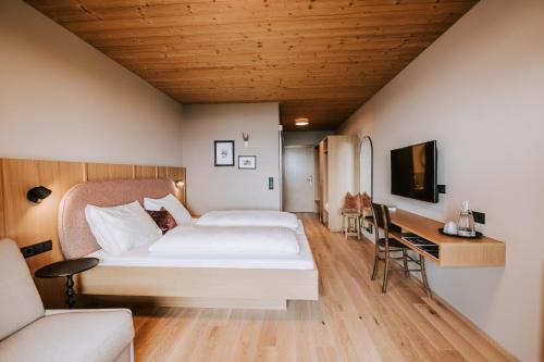 シュヴァルツェンベルク・イム・ブレゲンツァーヴァルトにあるHotel Marviaのベッドとデスクが備わるホテルルームです。
