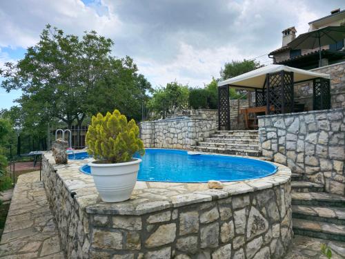 a stone retaining wall around a swimming pool in a yard at Kuća za odmor Ameli in Mošćenička Draga